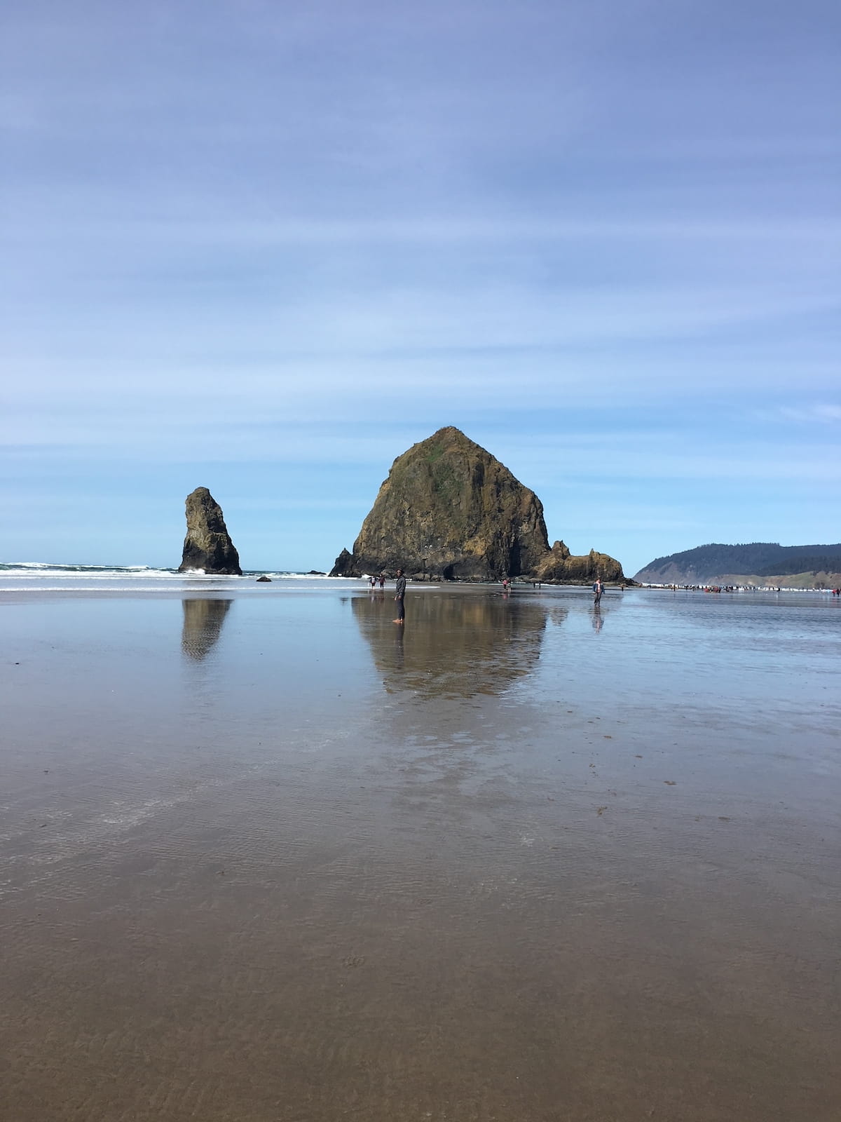 People in standing in shallow water near large rocks